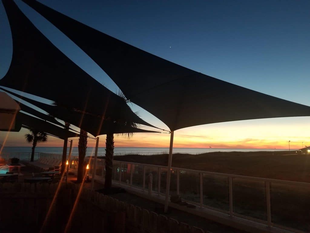 Sunset view of shade sails installed over a sitting area at The Tides Orange Beach by Emerald Coast Shade in Panama City Beach Florida